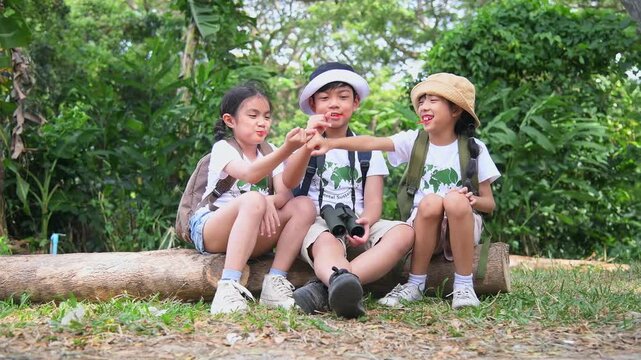 Children with binoculars holds hands and looks into distance and something joyfully screams they are wearing save world t-shirt with forest nature summer travel holiday concept.