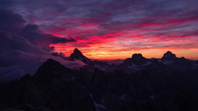 Time-lapse of dramatic clouds rolling fast over mountain peaks at sunset
