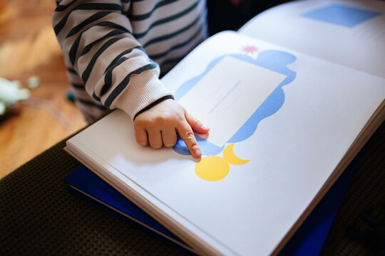 Toddler Reading Picture Book With Small Hand Pointing