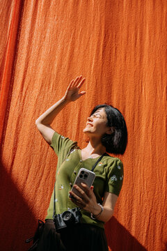 Woman enjoys sunlight near an orange backdrop
