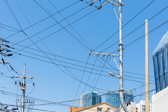 Utility pole with tangled power lines under clear blue sky