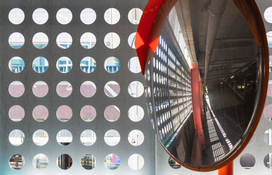 Convex mirror reflecting metal wall with cutouts in indoor garage