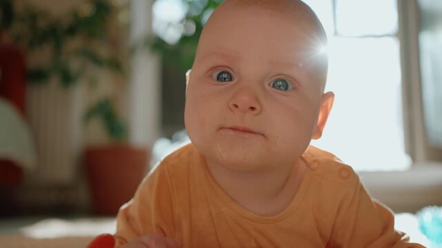 Curious baby with big blue eyes exploring the world during tummy time. Adorable newborn infant drooling while learning to crawl, showcasing innocence and early development in a bright room