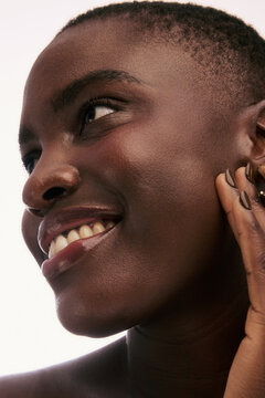 Woman Smiling With Her Hand on Her Cheek in a Bright Setting