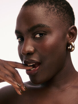 Model Poses With Finger Near Lips in Studio Setting