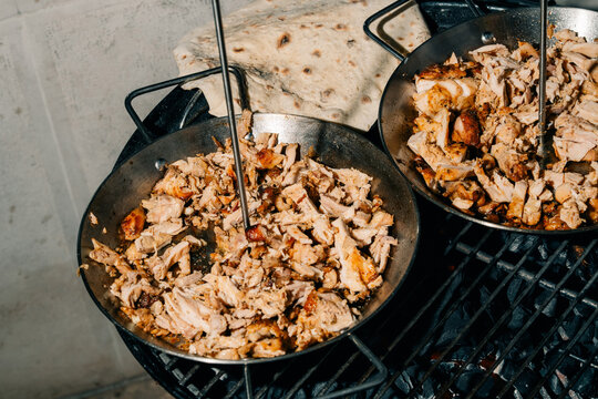 Cooking Meat in Large Pans Over an Open Flame at a Gathering