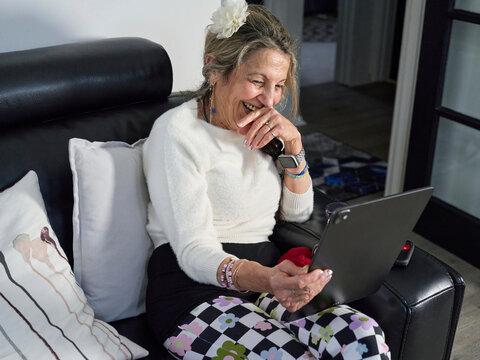 Elderly Woman Smiles During Video Call While Sitting on Couch
