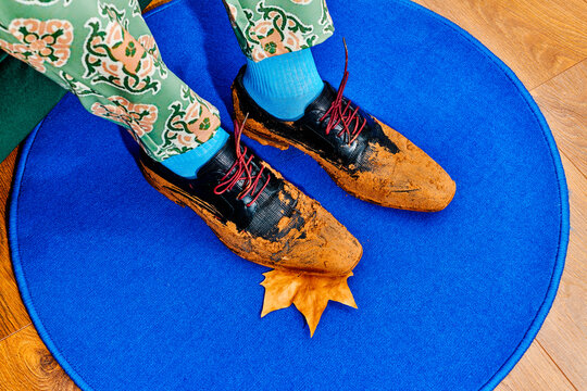 a seated man with one muddy shoe over a fallen autumn leaf