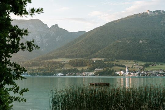 View across Wolfgangsee framed by trees with mountains rising ab