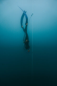 freediver moving vertically through deep lake water