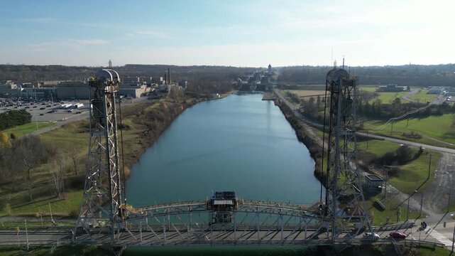 Aerial lifting up over the Welland Canal and Glendale Avenue Lift Bridge, St. Lawrence Seaway, St. Catharines, Ontario, Canada. View towards lock 5 in Thorold. Autumn, 2024.
