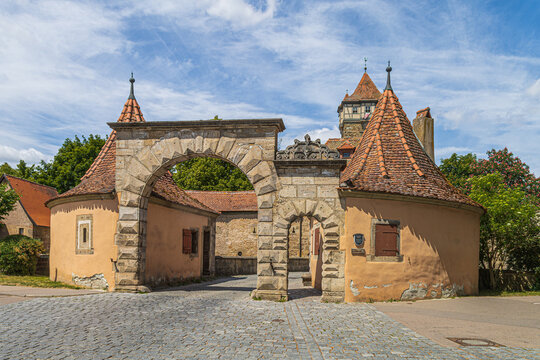 Rothenburg ob der Tauber, Bavaria, Germany: The medieval R&ouml;dertor gate tower, double stone arches and red-roofed guardhouses forming part of the town's historic fortifications.