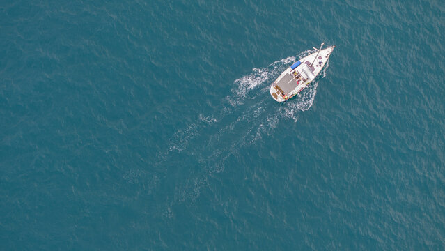 Aerial top view of sailing boat cruising on turquoise sea