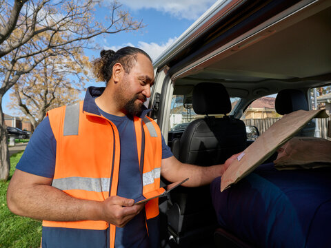 Worker Checks Package in Delivery Van on a Sunny Day