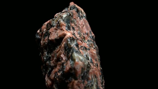 Granodiorite (phaneritic-textured intrusive igneous rock similar to granite, but with more plagioclase feldspar than orthoclase feldspar) rotating slowly against a black background [from Norway]