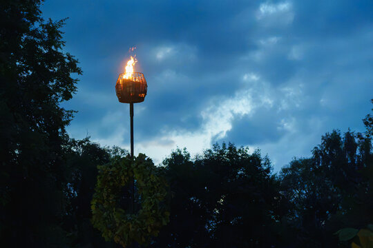 Elevated Fire Basket with Burning Flame and Oak Wreath at Twilight