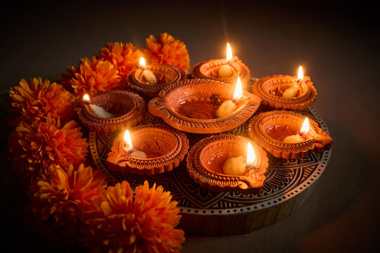 Diwali clay oil lamps with glowing flames and marigold flowers