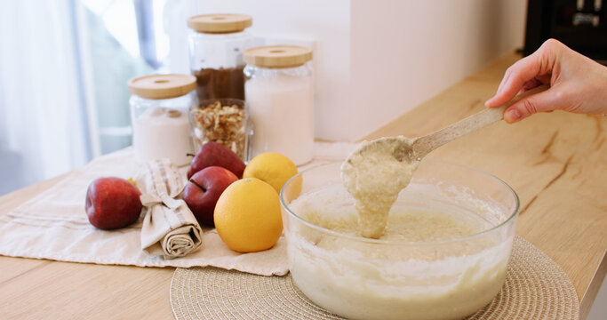 Cooking process. Pastry recipe. Woman chef hand checking thick liquid dough preparation with spoon on wooden kitchen table with fruit.