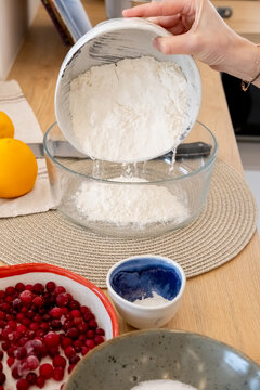 Pouring flour. Dough preparation. Female baker hand cooking sweet wheat pastry on home kitchen table with baking ingredient bowl set.