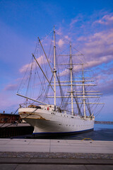 Fototapeta premium Historic Sailing Ship Docked at Sunset in a European Harbor