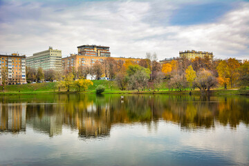 Autumn view across Bolshoy Novodevichy Pond in Moscow, Russia, with city buildings reflected in calm water. Useful for travel, urban park, seasonal and cityscape themes © Kate