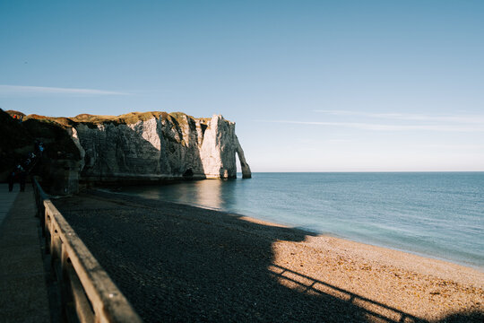 Chalk cliffs of Etretat rising above the pebble beach along the English Channel during a sunny day