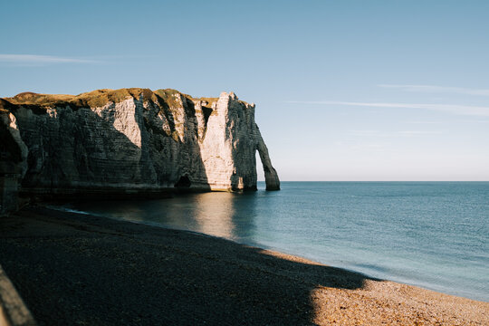 Chalk cliffs and natural arch at Etretat beach during a calm sunny afternoon in Normandy France