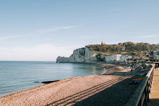 White limestone cliffs overlooking the pebble beach at Etretat during a calm morning in Normandy