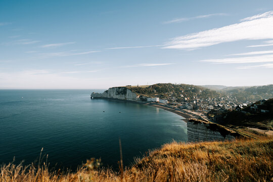 White cliffs overlooking the coastal town of Etretat in Normandy during a bright sunny afternoon