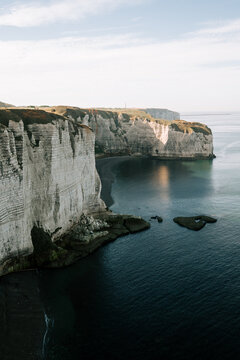 White chalk cliffs of Etretat rising above the calm waters of the English Channel during the morning