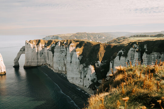 White chalk cliffs and natural rock arch at Etretat beach during a calm morning in France