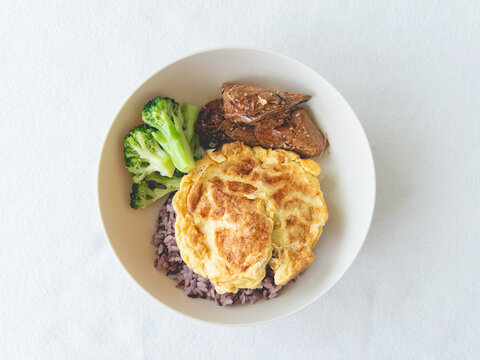Healthy home-cooked meal with omelet, broccoli, and rice, promoting a balanced and nutritious diet.