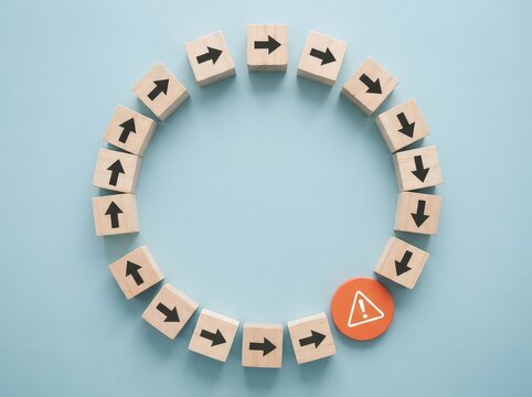Wooden blocks arranged in a circle with arrows pointing in a clockwise direction and one orange warning sign