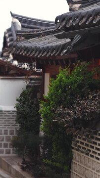Bukchon Hanok Village in Gahoe-dong, Jongno-gu, Seoul, South Korea, street with traditional Korean hanok houses, giwa tiled roofs and white walls in a narrow alley on a sunny spring day