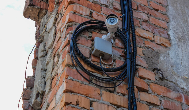 Security surveillance camera and wiring mounted on old brick building wall