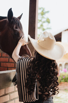 woman in a cowboy hat touching a horse