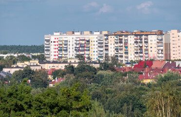 Ostrowiec Świętokrzyski – widok na miasto późnym letnim popołudniem. W tle widać wysokie bloki mieszkalne o kolorowych elewacjach, natomiast na pierwszym planie znajdują się domy mieszkalne z czerwony © Grzegorz