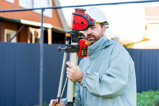 Engineer using laser level with receiver on tripod at residential construction site