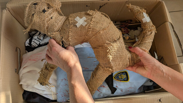 Hands unpacking Halloween decorations from a cardboard storage box. 