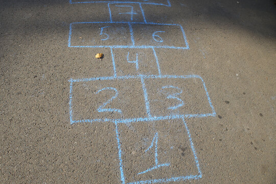 Hopscotch grid drawn in blue chalk on an asphalt path