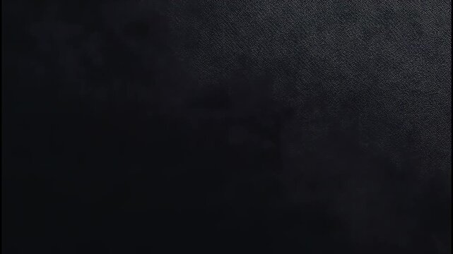 Dark black textured background with a fine diagonal weave pattern and subtle light reflection 4k video