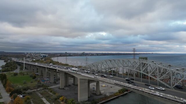 Aerial over Hamilton Harbour, Burlington Skyway and Burlington Canal Lift Bridge in Hamilton, Ontario, Canada along the QEW. Shot on autumn evening right before sunset, October, 2024.