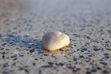 A macro shot of a natural, smooth pebble. The contrast between the organic shape of the stone and a mosaic concrete surface. Ideal for themes related to urban lifestyle, street games, hobbies.. © Inna