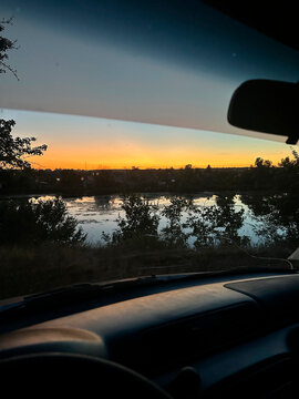 Sunset lake landscape viewed through car windshield interior