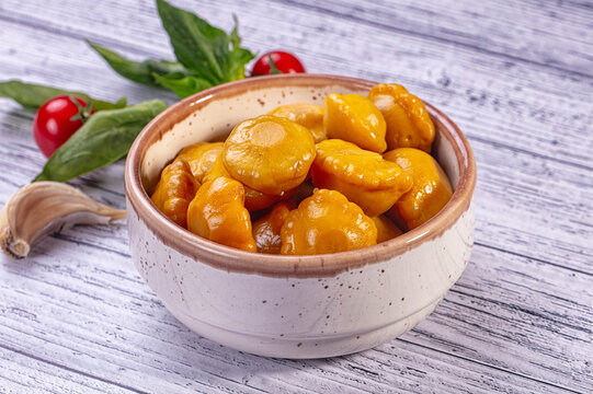 Light wooden surface with ceramic bowl of yellow patisson squash, marinated vegetable appetizer