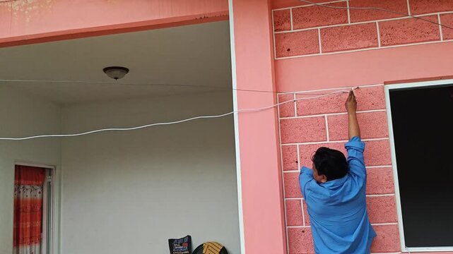 Young Man Routing Internet Cable Along Wall