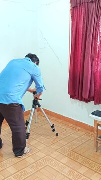 Young Man Adjusting Height Legs of Camera Tripod