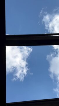 sky and clouds a bright blue sky with white clouds viewed through a window frame.