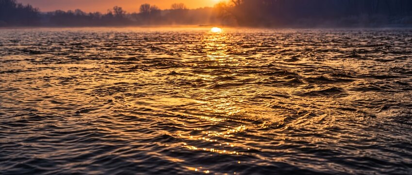 Golden sunset reflection on flowing water surface in nature landscape