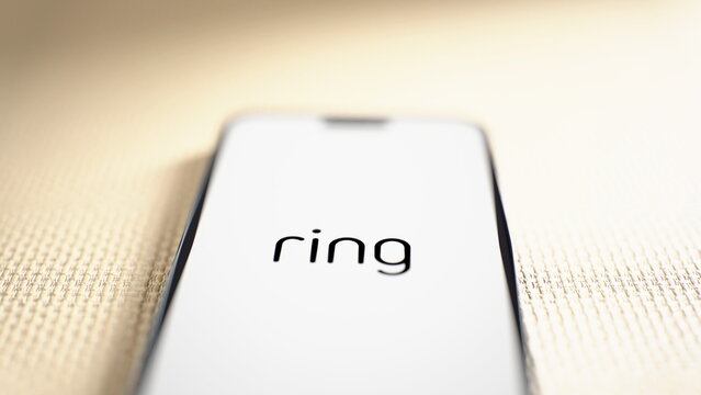 Low-angle view of the Ring logo displayed on a smartphone lying on a fabric surface. Ring Unveils $249 Smart Lock With Hand-Crank Backup Charging, Five New Cameras. October 8, 2026, Lisbon, Portugal.